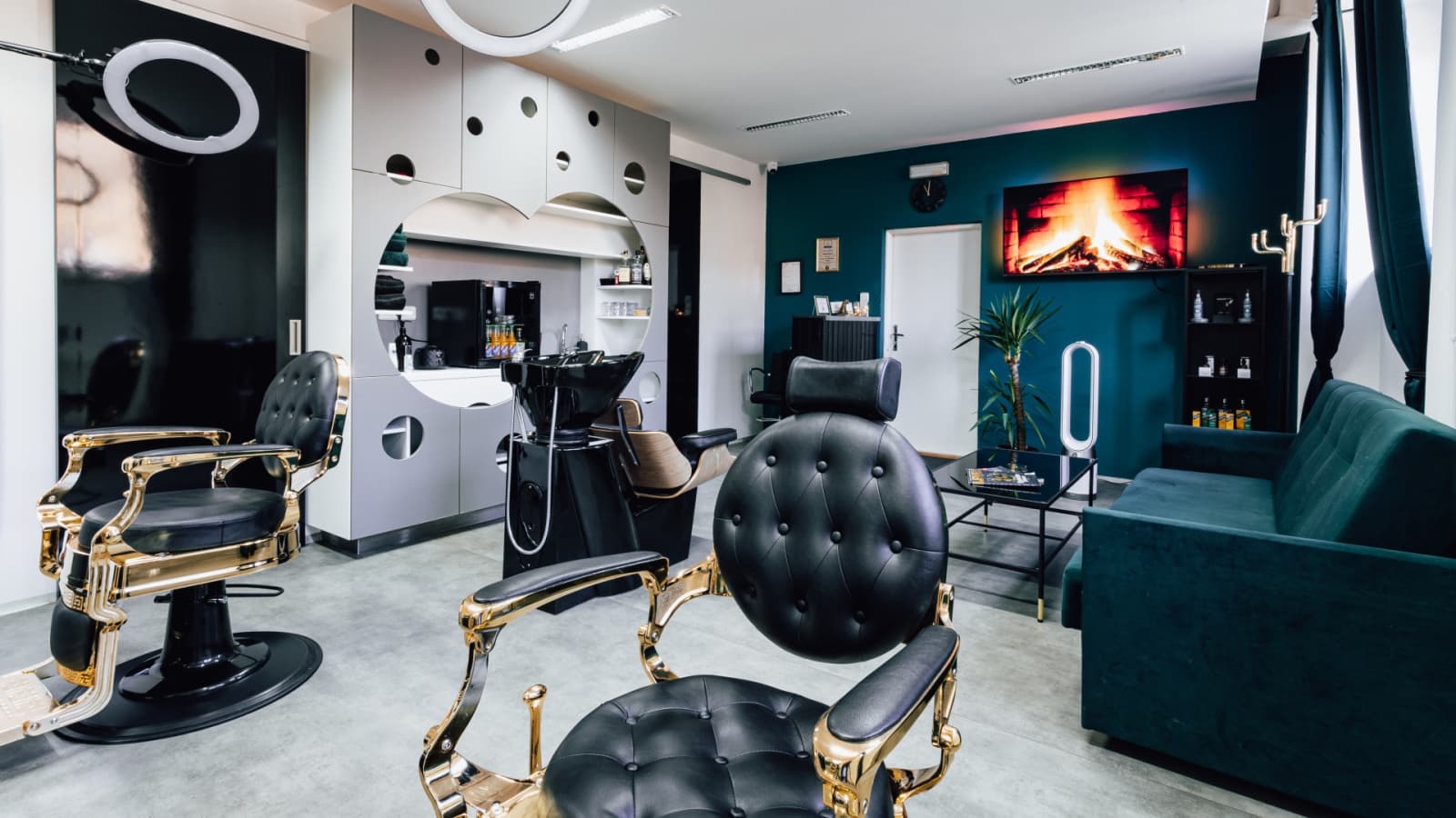 Interiér Platini Barber: zlatá barberská křesla, zelená stěna a krb